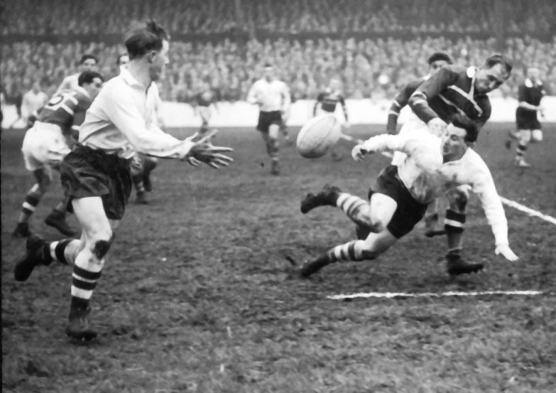 Frank Pitchford releases the ball to Vince Nestor when collared by a Hornets defender - April 22nd 1957.