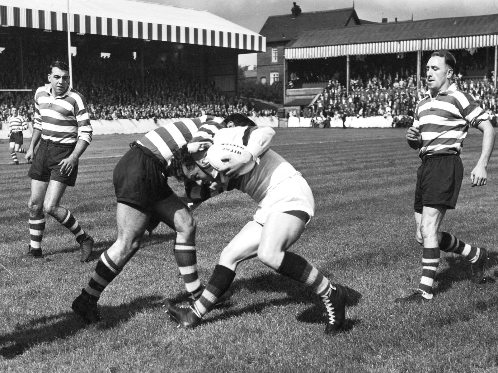 Dick Cracknell (left) and Frank Stirrup look on as a team-mate bring down a Whitehaven player - Aug 30th 1958.