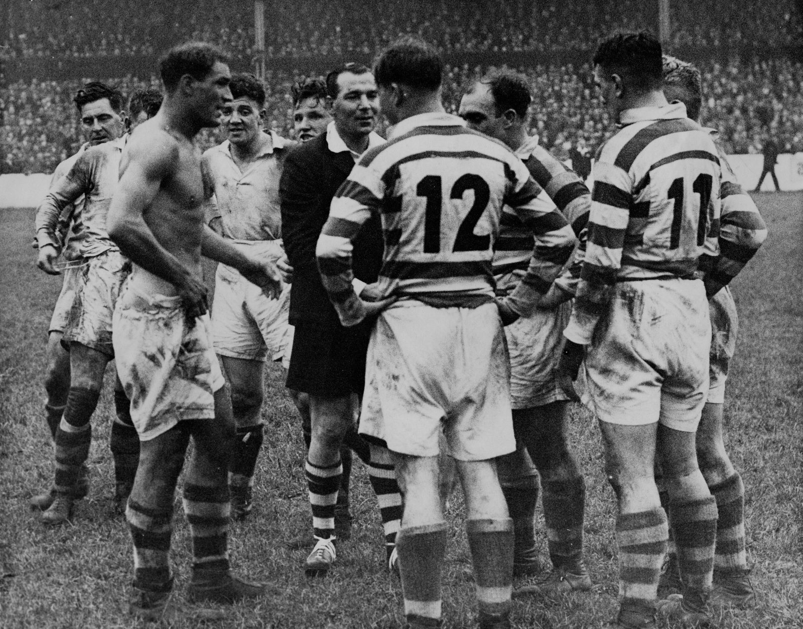 The referee sorts out a disagreement between a shirtless Doug Phillips and the Wigan forwards - Oct 15th 1946.