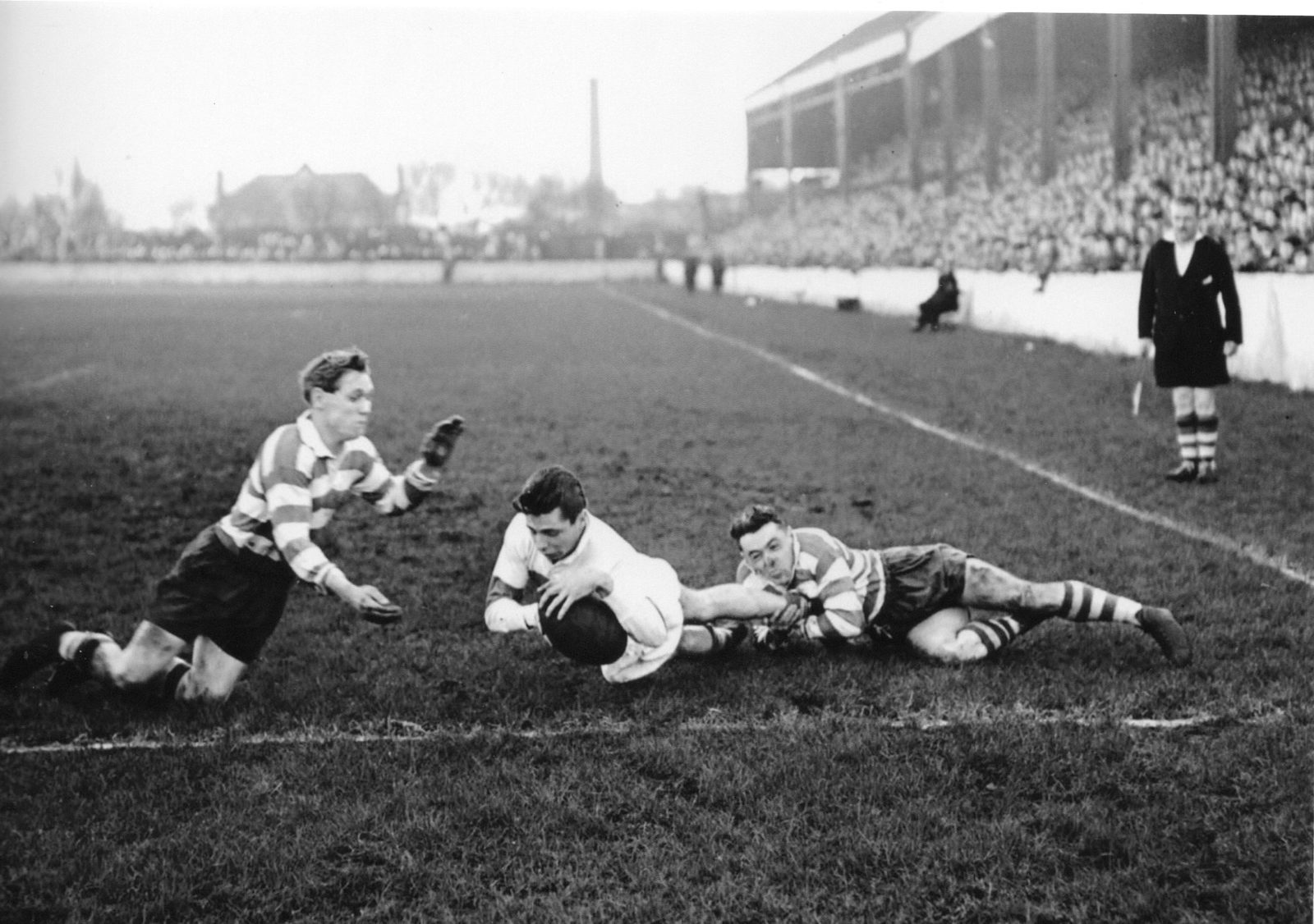 Bailey, the Workington left wing scores one of his two tries despite the tackle of Bernard Ganley and John Feather - Dec 19th 1953.