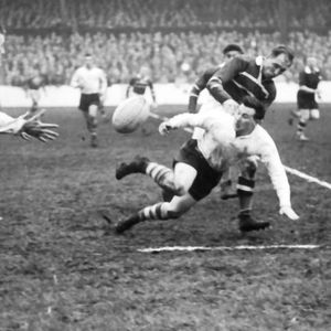 Frank Pitchford releases the ball to Vince Nestor when collared by a Hornets defender - April 22nd 1957.