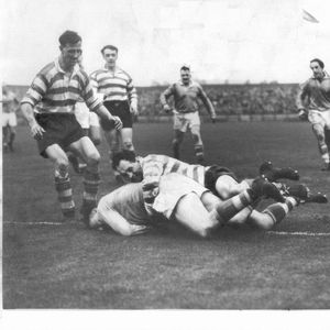 Sid Little brings down a Saints player with Jack Keith, Bernard Ganley, Tom McKinney, Walter Delves, and Ken Jackson in …